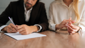Cropped shot of spouses couple signing decree papers getting divorced in lawyers office at desk. Unhappy married family split break up end relationships giving permission to marriage dissolution.