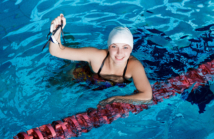 smiling woman in swimming hat and glasses in swimming pool